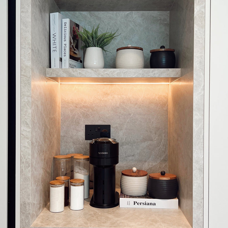 Shelving unit with decorative items including books, plants, and a coffee maker. - Casa Eva | Home Organizing & Style